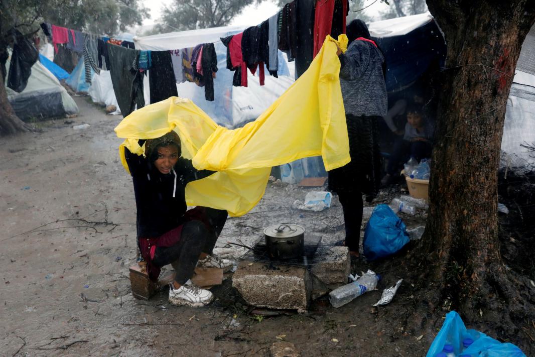 A girl tries to protect herself from the rain at a makeshift camp for refugees and migrants next to the Moria camp during a rainfall, on the island of Lesbos